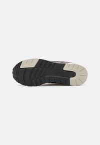 Adidasova potplat s crnim gumiranim dnom, koji sadrži teksturirani uzorak i kremaste akcenate. Izdržljiv dizajn za prianjanje.