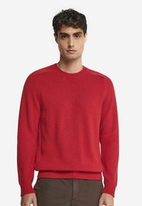 Röd stickad tröja med rundad halsringning, ribbade muddar och nederkant, med en mjuk textur och en avslappnad passform.