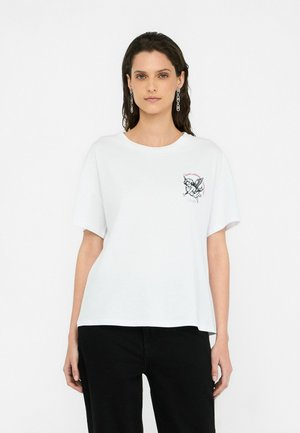 T-shirt en coton blanc à manches courtes, col rond, avec un design brodé sur la poitrine et une coupe décontractée.