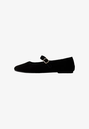 Black flat Mary Jane shoe with a rounded toe and a single strap featuring a gold buckle on white background.