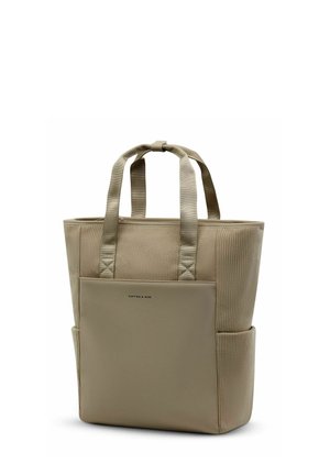 Sac fourre-tout beige avec côtés en tissu côtelé, poche avant lisse, deux poignées et poches latérales, debout sur fond blanc.