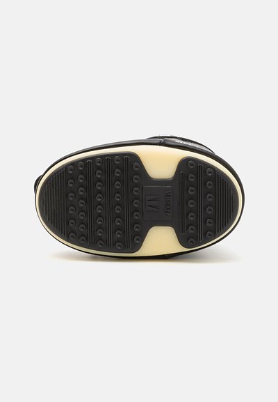 Black sneaker sole with textured rubber surface, featuring circular grip patterns and a smooth midsole. Minor branding on side.
