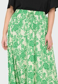 Gonna lunga con motivo floreale verde, dotata di una vita elasticizzata e di stringa di regolazione. Tessuto leggero, design a lunghezza completa, con grandi motivi di fiori e foglie.