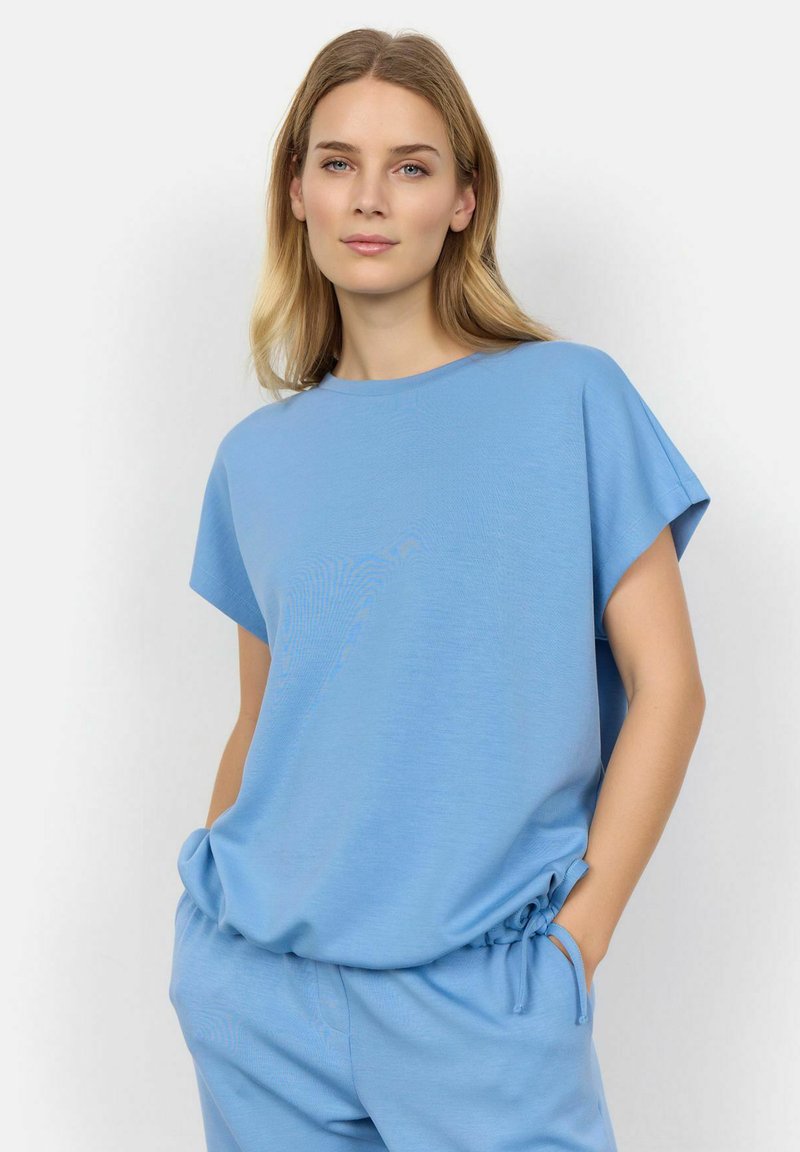 Světle modrý top s krátkým rukávem vyrobený z hladké tkaniny s volným střihem. Design s kulatým výstřihem a mírně zaoblenými švy na ramenou.