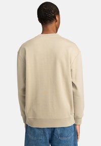 Beige sweatshirt med rund hals, ribbstickade ärmslut och nederkant. Mjukt tyg med en slät yta. Avslappnad passform, visad bakifrån.