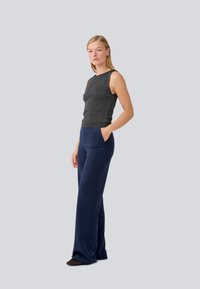Gray knit sleeveless top paired with navy wide-leg trousers. Trousers feature pockets and a smooth texture, while the top is fitted.