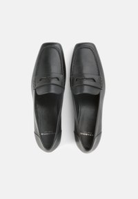 Μαύρα δερμάτινα μοκασίνια με λείο φινίρισμα, που διαθέτουν διακοσμητ ικό λουράκι στον κουντεπιέ και επένδυση για άνεση.