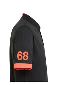Polo shirt nera con colletto arancione e dettagli arancioni sulle maniche, con un grande "68" ricamato in arancione sul braccio destro.