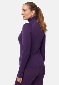 Violetti pitkähihaisen paita, jossa on korkea kaulus, slim fit, pehmeä pinta ja sormivälihaarat. Kangas vaikuttaa joustavalta ja mukavalta aktiiviseen käyttöön.