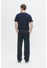 Navy short-sleeve t-shirt with a crew neck paired with black, loose-fit pants featuring back pockets and a small red logo on the waistband.