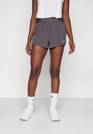 Grå Nike treningsshorts med elastisk midje, et reflekterende logo og en pustende stofftekstur, parret med hvite treningssokker og sko.
