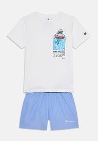T-shirt en coton blanc avec un graphique de requin et du texte, associé à un short de bain bleu clair, avec une ceinture et un détail de logo.
