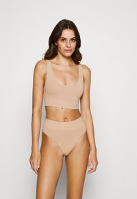 Beige bra and high-waisted brief set, crafted from smooth fabric. Features wide straps and a comfortable elastic waistband. Simple design.