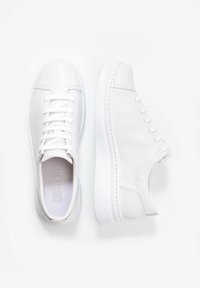 Zapatillas blancas de cuero con textura suave, punta redonda y suela plana de goma blanca. Presentan un diseño minimalista y cierre de cordones.