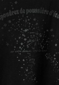 Material negru cu model de stele argintii și text tipărit într-un font jucăuș, cu fraze legate de praf de stele și lună.