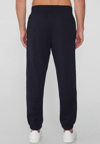 Pantalones deportivos azul marino hechos de una tela suave, con cintura y puños elásticos, además de bolsillos laterales para mayor practicidad.