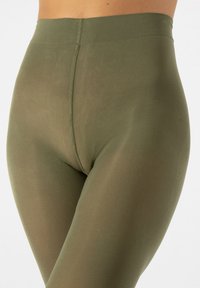 Leggings verde oliva con una cinturilla alta, que presentan una textura suave y elástica y un diseño ajustado. Las costuras son visibles a lo largo de los lados.