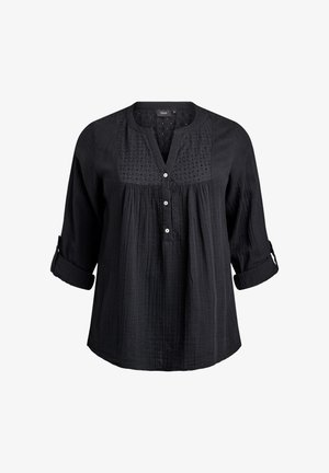 Blouse noire à manches longues avec trois boutons blancs, empiècement brodé, devant plissé et manches retroussées avec pattes à boutons.