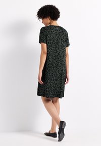 Robe verte à manches courtes avec imprimé léopard noir, longueur genoux, en tissu doux, dotée d'un col rond et d'une coupe ample.