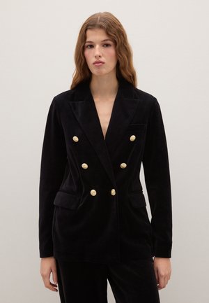 Blazer de terciopelo negro de doble botonadura con botones dorados, solapas muesca, bolsillos frontales y un diseño ajustado y elegante.