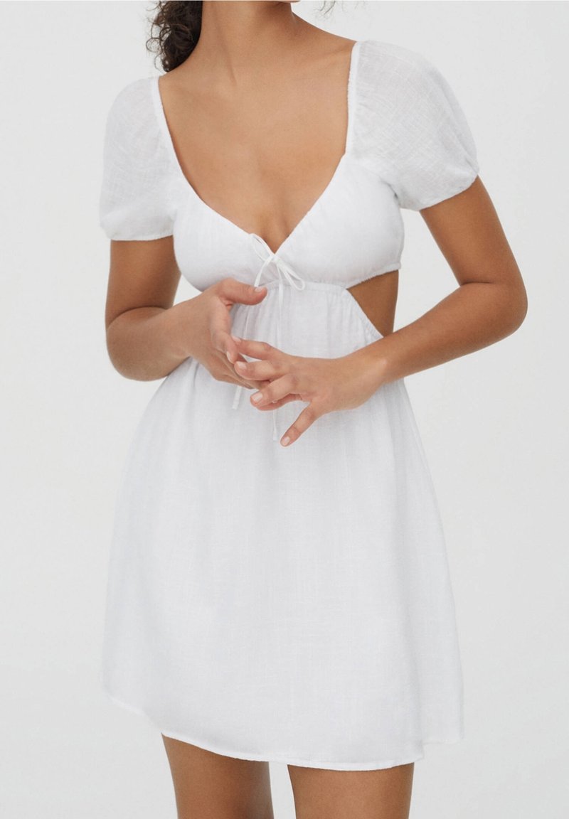 Robe blanche avec un décolleté en V profond, des manches bouffantes, un détail à cordon de serrage à la taille et des découpes sur les côtés, confectionnée dans un tissu léger.