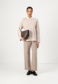 Striped long-sleeve top in light tan, cream, and lavender; paired with beige wide-leg trousers; holding a dark brown clutch; black loafers.