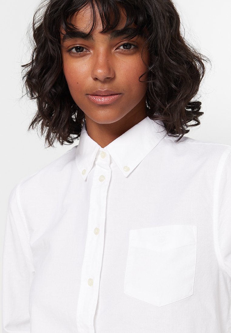 Weißes Hemd aus Baumwolle mit klassischem Kragen, einer Brusttasche und dezentem Logo-Detail über der Tasche.