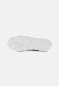 Sola de ténis branca com padrão ondulado texturizado e detalhe do logótipo. Material suave de borracha com uma borda ligeiramente elevada que contorna a forma.