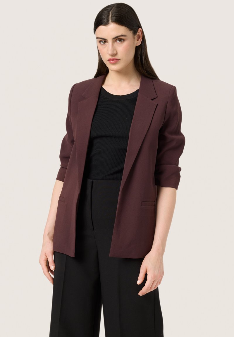 Mauve blazer with a tailored design, notched lapels, and three-quarter sleeves. Paired with a black ribbed top and black wide-leg trousers.