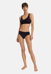 Set di bikini nero con un tessuto morbido e elasticizzato. Il top presenta un collo a giro e spalline larghe; il fondo ha un taglio a vita bassa.
