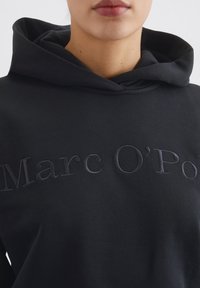 Felpa nera in cotone misto, con logo ricamato tono su tono sul davanti. Il cappuccio ha un design a doppio strato per un effetto di maggiore texture.