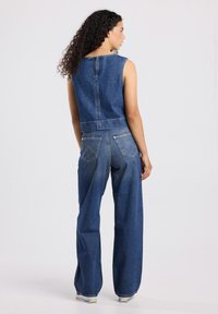 Denim set includes a sleeveless cropped top and wide-leg jeans, both in blue. Notable details: high waist, back zip, and stitch accents.