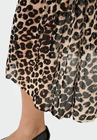 Plāns svārks no caurspīdīga materiāla ar leoparda rakstu, kas ietver bežīgas, melnas un brūnas nokrāsas; gluda tekstūra ar plūstošu kustību.