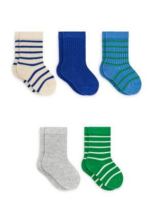 Cinq paires de chaussettes d'enfants pliées beige à rayures bleues, bleu uni, bleu à rayures vertes, gris et vert à rayures blanches sur fond blanc.