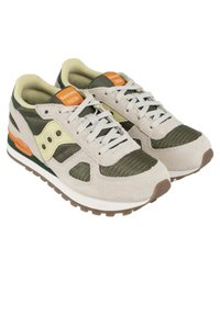Las zapatillas Saucony Shadow cuentan con una combinación de malla verde oliva y ante gris claro, detalles en naranja y una media suela blanca con una suela exterior texturizada marrón.