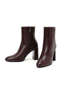 Stivaletti alla caviglia in ecopelle borgogna con punta affusolata, chiusura con zip laterale e tacco a blocco largo. Texture liscia e silhouette elegante.