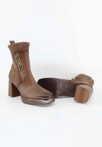 Stivaletti con tacco marroni realizzati in pelle e suede con una finitura liscia, caratterizzati da due bottoni rotondi dorati e un tacco a blocco testurizzato.