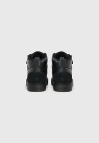 Black high-top sneakers with leather and suede materials, featuring a textured finish, padded collar, and a rubber sole. Minimal branding visible.