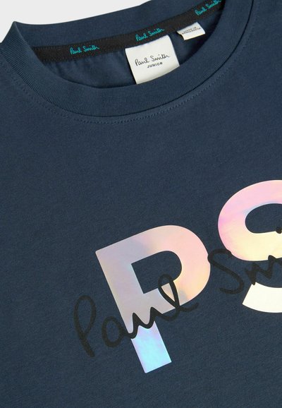 Tamsiai mėlyna medvilninė marškinėliai, kuriuose yra didelis mirdintis "PS" grafikas ir juoda parašo šriftas. Apvalus iškirpimas su lygiu paviršiumi.