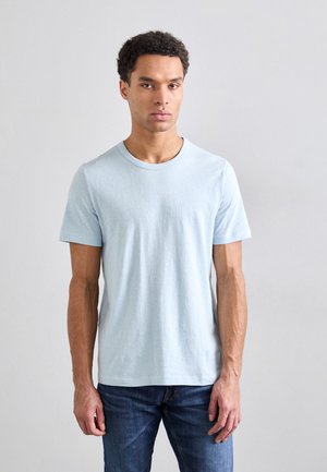 T-shirt azzurro a maniche corte in cotone con scollatura rotonda e texture liscia, abbinato a jeans in denim blu.