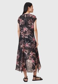 Abito lungo nero a fiori con maniche a cappuccio, con motivi di fiori rosa e marroni. Tessuto leggero e semitrasparente con orlo asimmetrico.