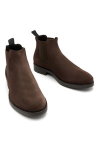 Brązowe zamszowe botki za kostkę mają elegancki design, elastyczne boczne panele oraz pętelkę, z gładką podeszwą i kontrastowymi ciemnymi wykończeniami.