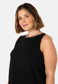 Schwarzes ärmelloses Top mit rundem Ausschnitt und feinen Nahtdetails. Weicher Stoff mit glatter Textur, geeignet für die Freizeit.