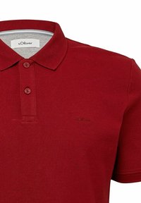 Rotes Poloshirt aus strukturiertem Stoff, mit einem klassischen Kragen, zwei Knöpfen und einem dezenten gestickten Logo auf der Brust.