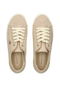 Scarpe da ginnastica in tela beige con lacci bianchi, dotate di punta tonda e logo ricamato sul lato. Texture liscia con un design casual.