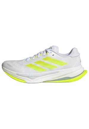 Scarpa atletica bianca con tre strisce giallo brillante, tomaia texturizzata, colletto imbottito e suola leggera con un accento verde neon in contrasto.