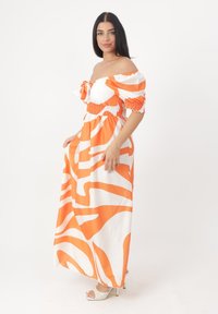 Maxikleid in Orange und Weiß mit schulterfreier Gestaltung, gerafftem Oberteil und auffälligem wellenförmigen Muster. Geschmeidiger Stoff, kurze Puffärmel.