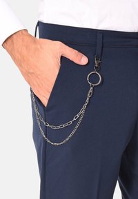 Pantaloni blu navy con una tasca anteriore e una catena argentata con dettaglio ad anello, appesa alla tasca per il fissaggio di accessori.