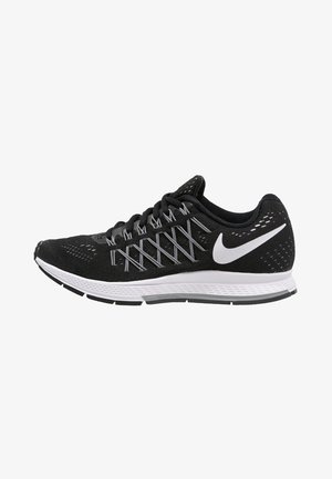 Chaussure de course Nike noire avec semelle blanche et détails argentés sur les lacets, avec un logo Nike blanc sur le côté.