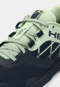 Heleroheline kergjooksujalanõu võrgust pealiskihi, tumesiniste detailide, tekstuurse tallaga ja dekoratiivse valge õmblusega. Omab lamedaid paelu ja brändingut.